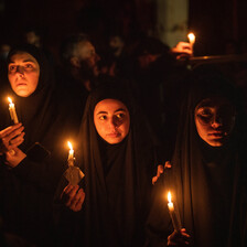 Dark clad girls hold up candles