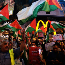 Palestinian flags waved by protesters obscure a McDonald's logo. 