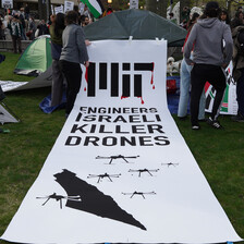 A banner on the ground at a student encampment reads MIT engineers Israeli killer drones