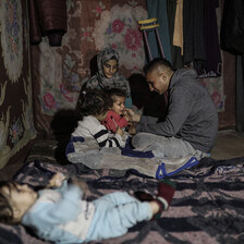 a family huddles together in their tent 