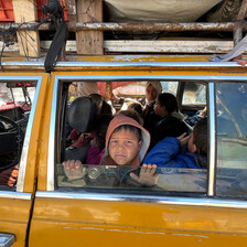 A boy looks out the window of fully loaded taxi