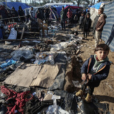 A boy stands next to a destroyed tent