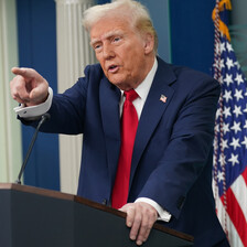 President Donald Trump points from podium with American flag behind him