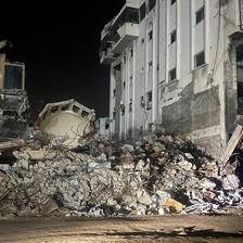 Floodlights at night shine on a building in ruins