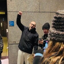 The Canadian activist Yves Engler raises his fist in the company of family and friends