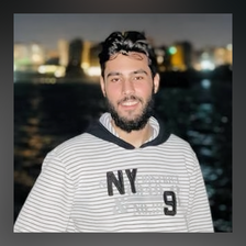 Smiling young man looks at camera with nighttime city skyline in background