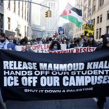 Protesters march with signs and a Palestinian flag