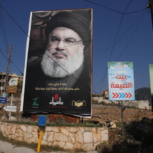 A large poster of Hasan Nasrallah displayed on a street corner