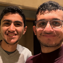 Two young men smile in a close-up portrait
