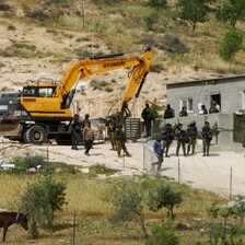 A Hyundai bulldozer and numerous Israeli troops beside a family's home in the occupied West Bank