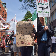 A man holds up a placard voicing support for Kneecap against genocide