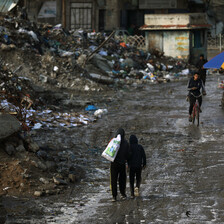 People wal;k past mountains of waste in Gaza