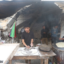 Two people make bread at a stall erected amid a badly damaged refugee camp in Gaza 