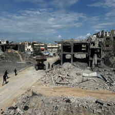 During the daytime, a road runs through bombed-out buildings.