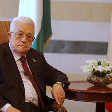 Mahmoud Abbas sits at a table next to some flowers