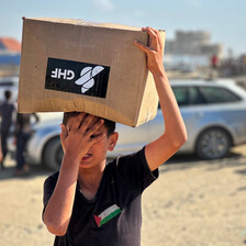 A boy carries a box as he and others seek aid 