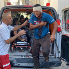 A bandaged man and a paramedic outside the back of an ambulance