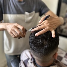 One man cuts another man's hair 