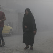 A young man and an older woman walk amid smoke following an Israeli airstrike on Gaza City 