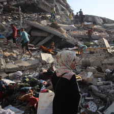A woman walks past the rubble of a bombed tower block
