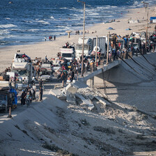 People walk beside a long convoy of trucks on the Gaza coast 