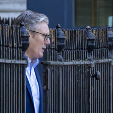 UK Prime Minister emerges from a metal fence
