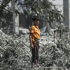 A boy wearing a bright yellow shirt stands in contrast to dust-covered environment around him