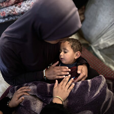 A woman seen from above cradles a baby in her lap