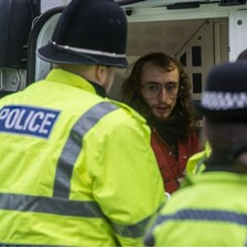 A man being put into a van by UK police