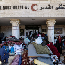 displaced people and their belongings in front of a hospital entrance