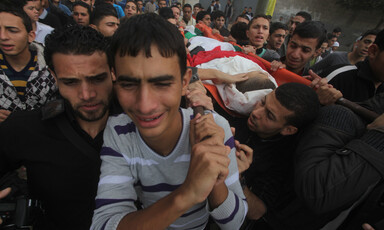 Young men carry body of slain man in funeral procession.