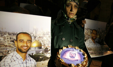 Woman holds a cake, surrounded by posters of prisoner