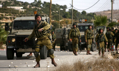 Soldier next to jeep throwing grenade. More soldiers nearby.