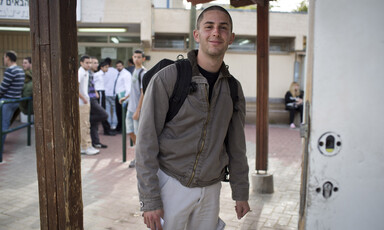 Smiling young man stands in front of building