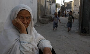 Elderly woman sits in refugee camp
