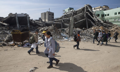 Children walk past rubble of destroyed buildings