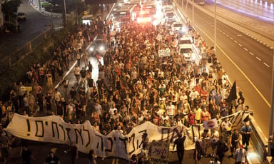 Protesters march down a highway carrying banners and signs