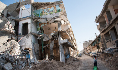 Boy walks past destroyed building exposing mural of Dome of the Rock in Jerusalem