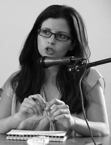 Portrait of seated Abir Kopty speaking into microphone