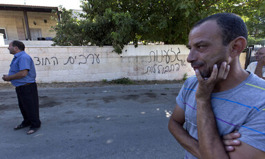 Men stand near wall sprayed-painted with graffiti