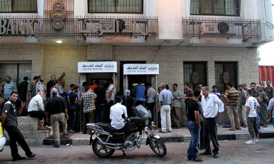 Men queue in front of bank building
