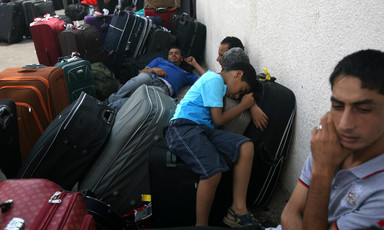 Men and boys sleep on suitcases