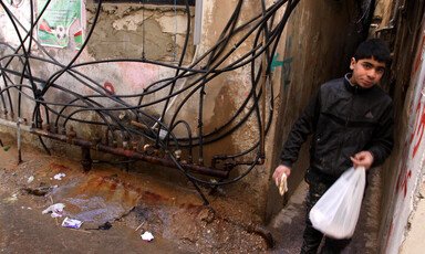 Youth walks in narrow alleyway where lots of electrical cables hang