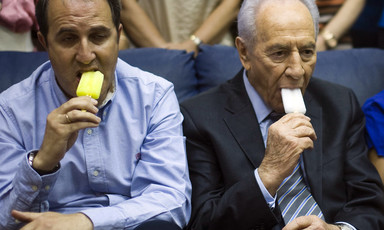 Two men, including Israeli president Shimon Peres, appear unhappy while eating ice cream
