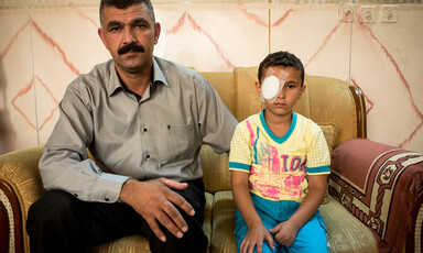 Man sits next to boy wearing cotton bandage eye patch