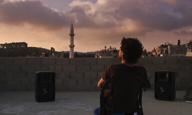 Man sits on chair overlooking city at sunset