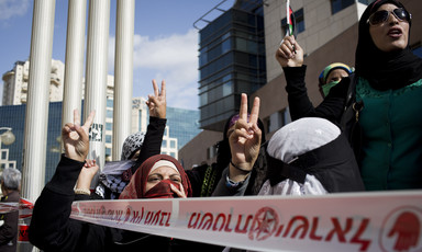 Women make victory sign with their hands during protest