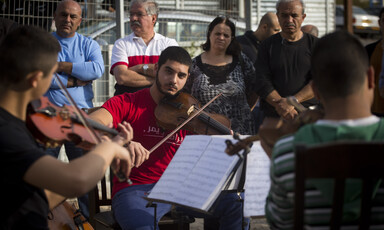 Young man plays the viola as others look on