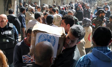 Man carries box of UN provisions amid crowd