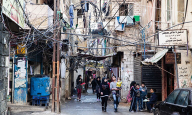 Scene of overcrowded refugee camp with cement buildings and lots of electricity wires